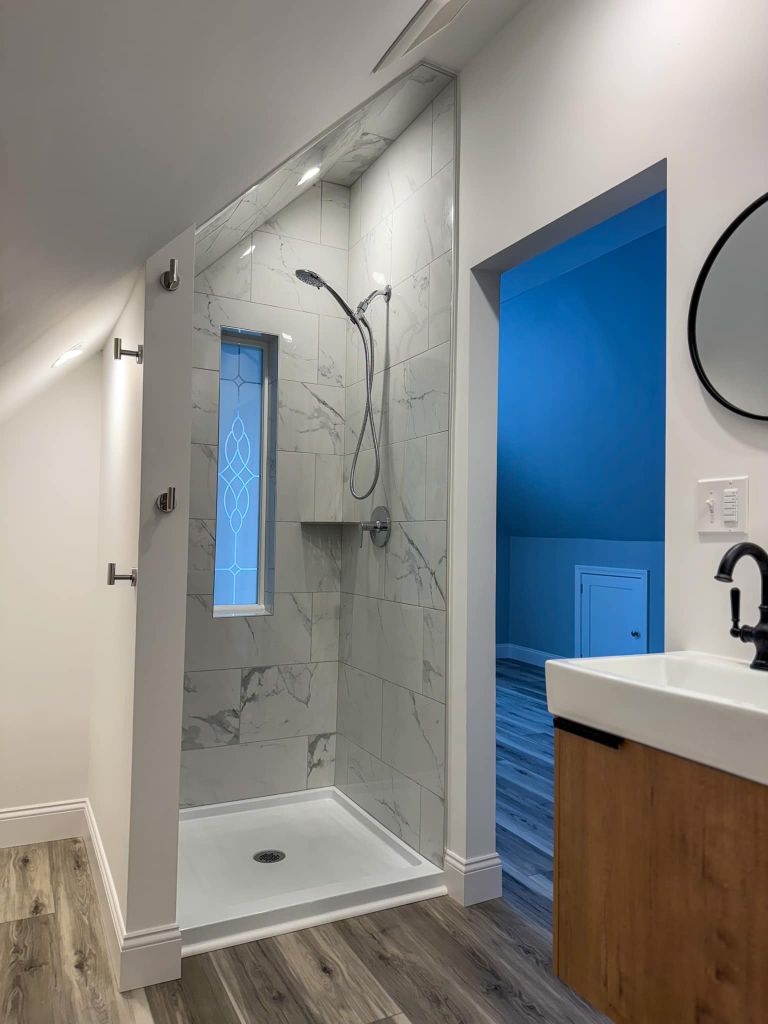 Bathroom renovation with marble shower and decorative window in Maine