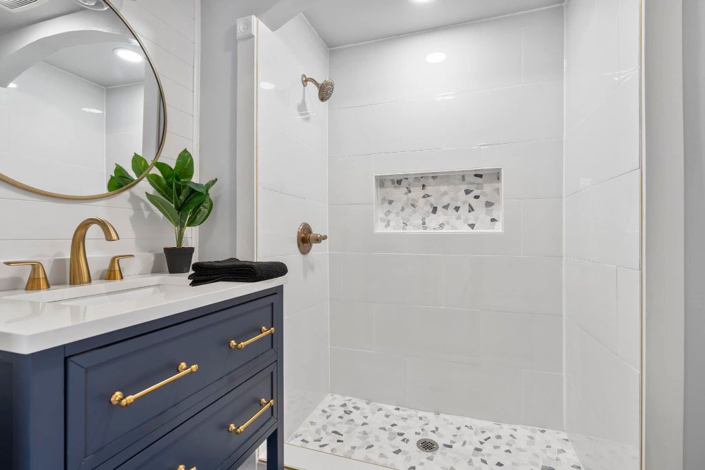 Luxury bathroom remodel with navy vanity and gold fixtures in Portland Maine